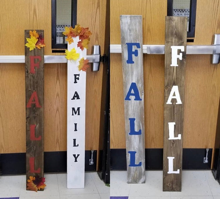 Wooden boards propped on a classroom door display the colorful wood stain and painted letters on top with a fall theme.